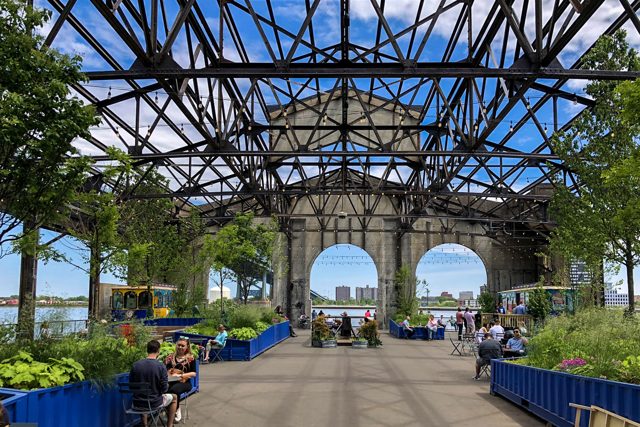 People at tables under the open steel roof of Cherry Street Pier